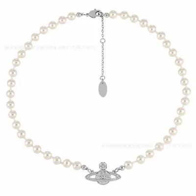 A pearl necklace laid out in a full circle, with a small silver pendant and a tag hanging at the clasp