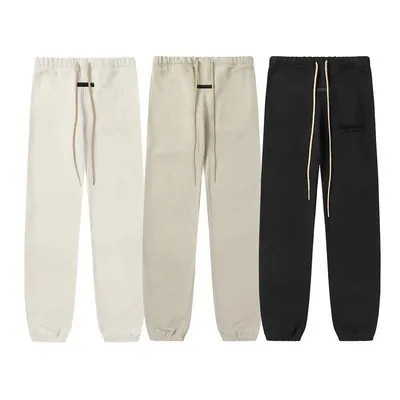 Three pairs of fleece joggers side by side, two in cream and one in black, each with a drawstring waist